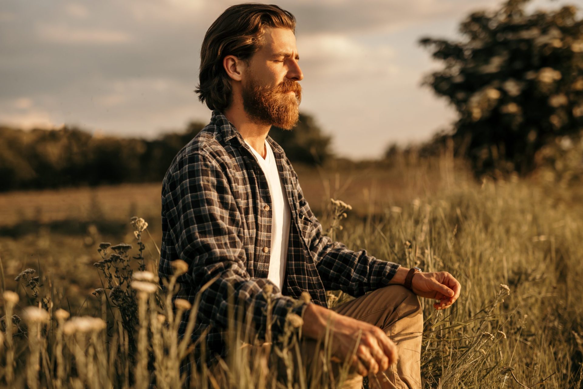 Un homme barbu médite dans une prairie