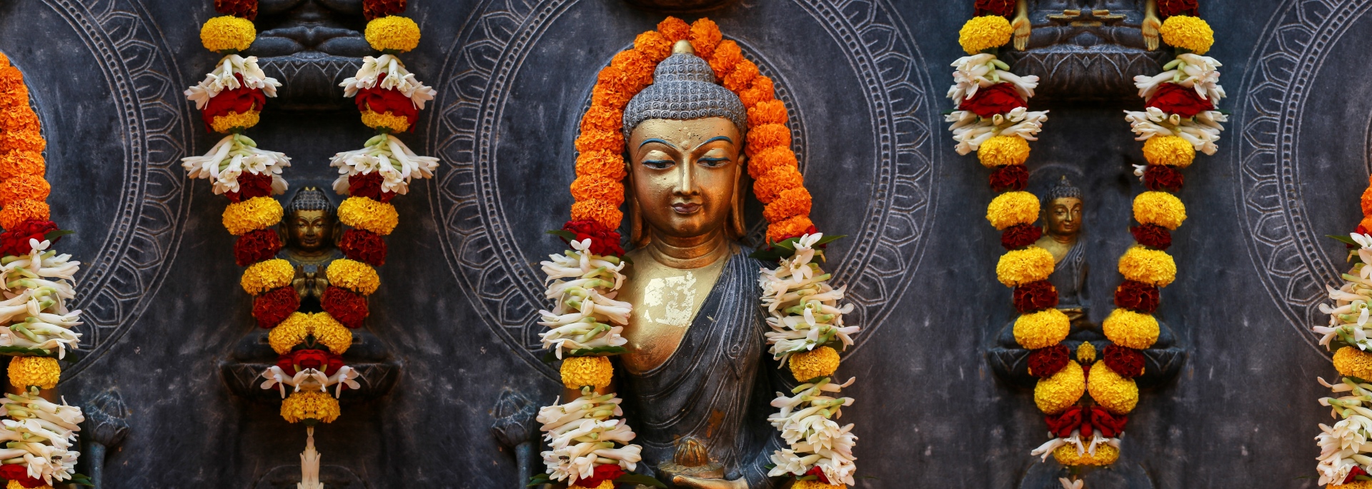 Une statue de Bouddha avec des colliers de fleurs